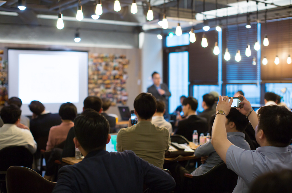 Presenter,Presenting,On,Stage,At,Conference,Meeting.,Professional,Lecture.,Blurred